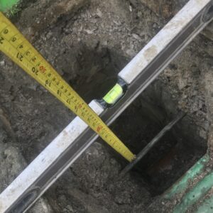 Groundworks for drainage pipes and utilities being measured for depth and level checked on a groundworks project in Wrexham